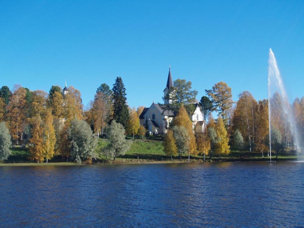 Haapajärven kirkko ruska-aikana, etualalla vettä ja suihkulähde