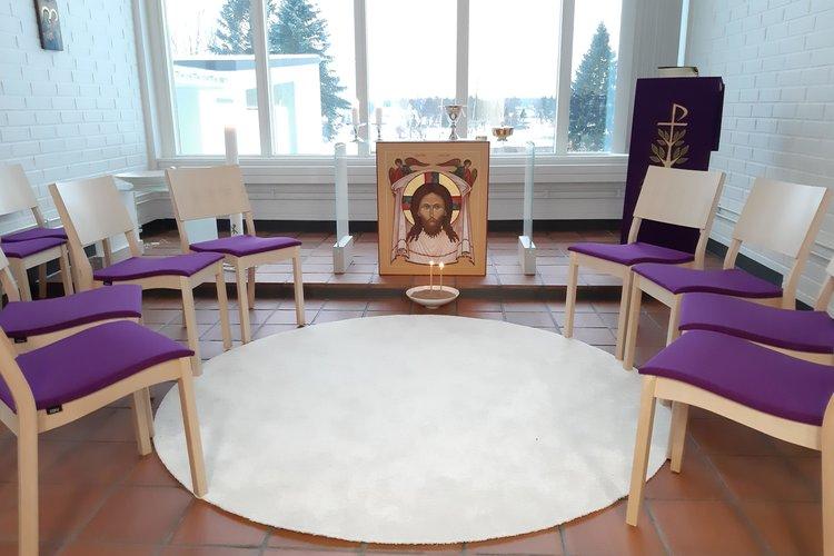 Kappeli, jossa tuoleja ympyrässä ja alttari, jossa Kristus-ikoni